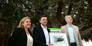 Presentando el cupón bajo el árbol centenario / FOTO: Eulogio García