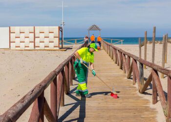 Retirando arena de una de las pasarelas / FOTO: Ayto.
