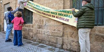 Colgando una pancarta reivindicativa en el antiguo ambulatorio / FOTO: Eulogio García