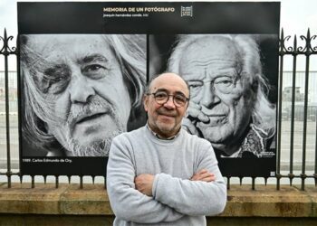 Kiki posando en la verja del muelle con una de sus exposiciones / FOTO: Eulogio García