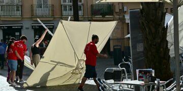 Camareros luchando con una sombrilla caída por el viento en una terraza / FOTO: Eulogio García