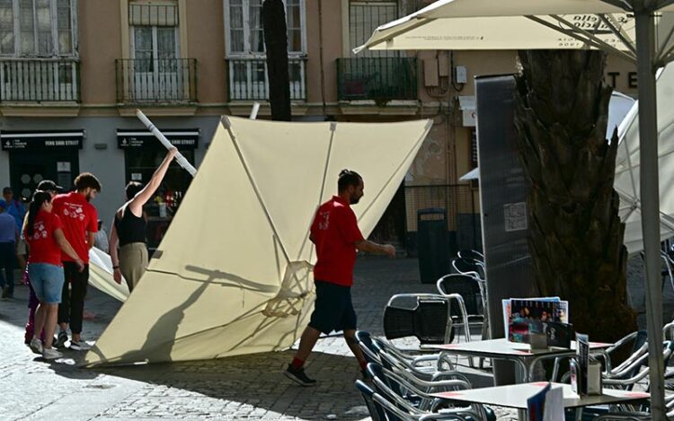 Camareros luchando con una sombrilla caída por el viento en una terraza / FOTO: Eulogio García